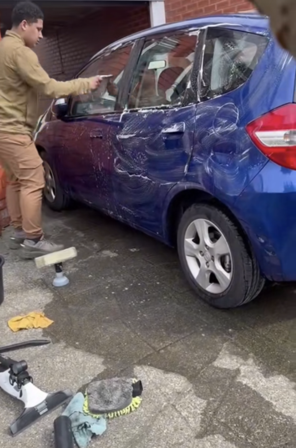 Hand washing a customer's car on a Liverpool driveway