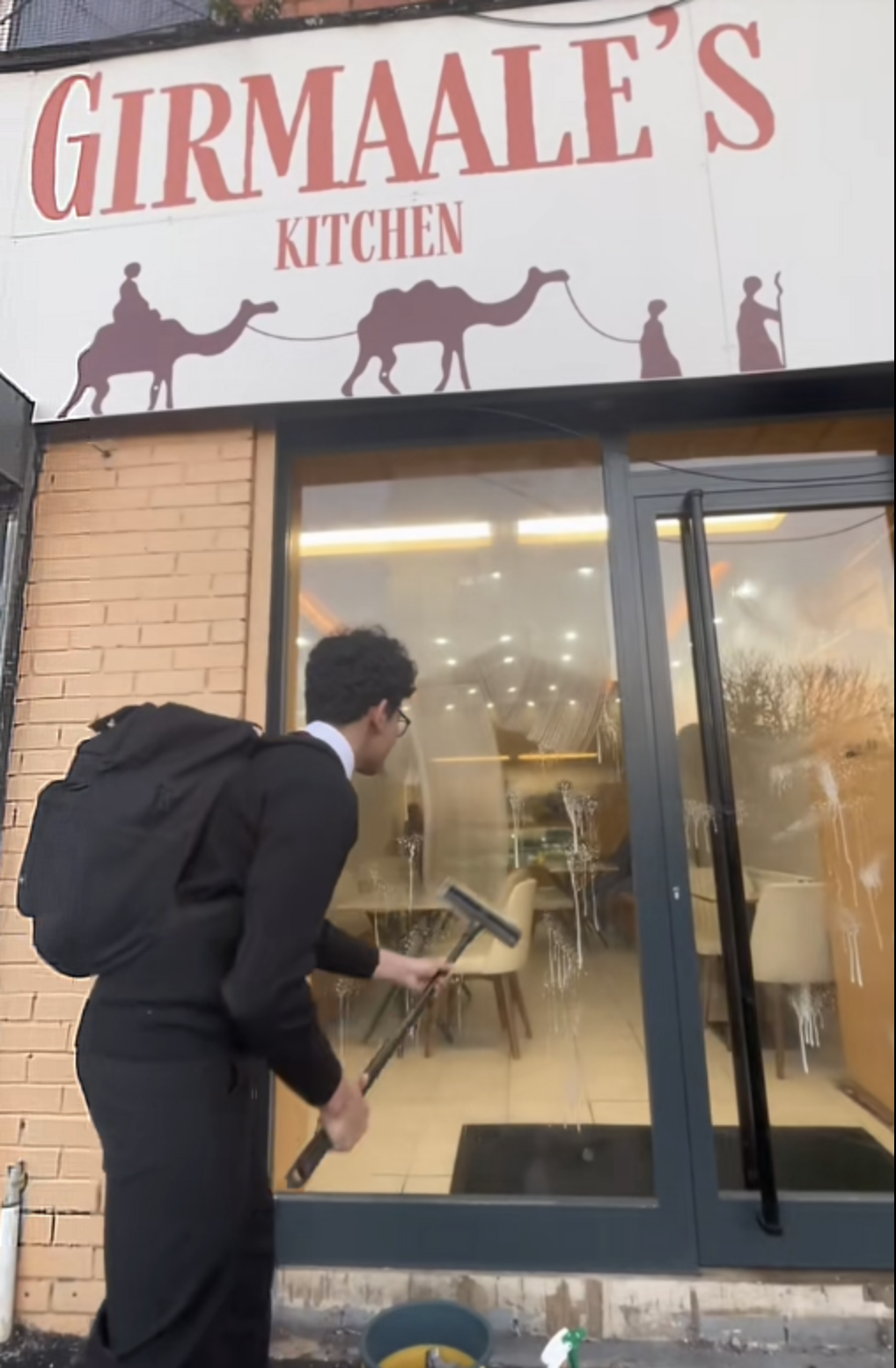 Cleaning the shopfront window at Girmaale's Kitchen, Liverpool