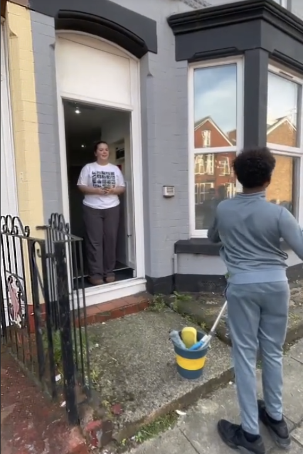 Cleaning bay windows at a Liverpool terraced home while the customer looks on
